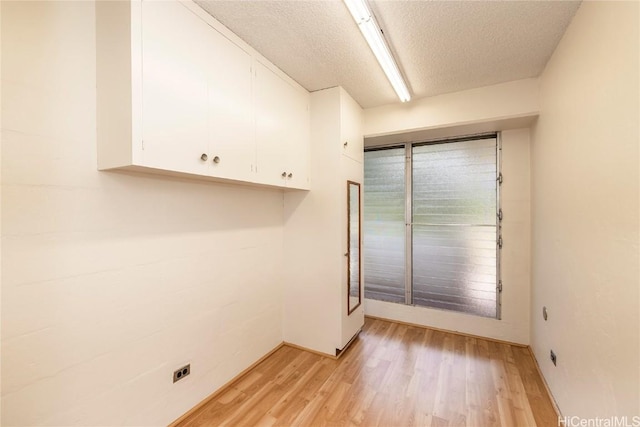 laundry area with cabinets, a textured ceiling, light hardwood / wood-style flooring, and electric dryer hookup