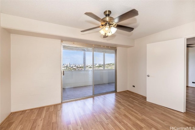 empty room featuring ceiling fan, a textured ceiling, and light wood-type flooring