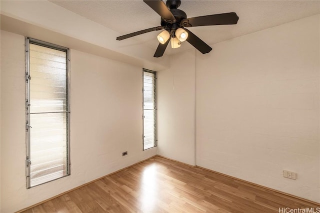 spare room with light wood-type flooring, ceiling fan, and a textured ceiling