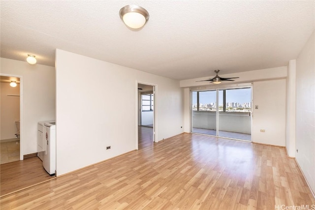 unfurnished living room featuring light wood-type flooring, a textured ceiling, washing machine and dryer, and ceiling fan