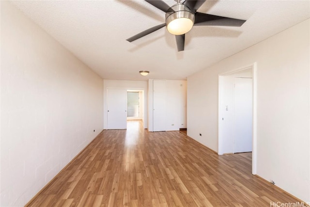 spare room with ceiling fan, light hardwood / wood-style floors, and a textured ceiling