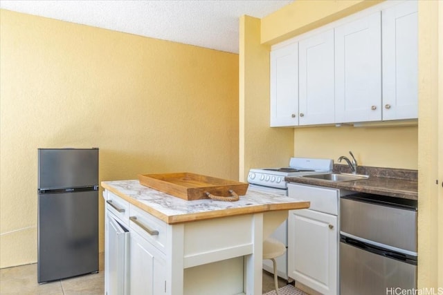 kitchen featuring white stove, white cabinets, sink, a textured ceiling, and stainless steel refrigerator