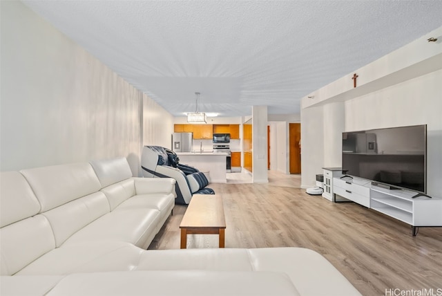 living room featuring light hardwood / wood-style floors, a textured ceiling, and a notable chandelier