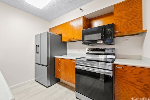 kitchen with stainless steel appliances, light hardwood / wood-style floors, and a textured ceiling