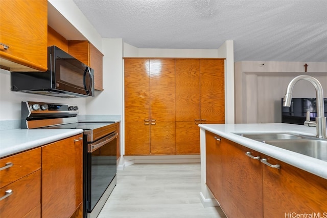 kitchen with light hardwood / wood-style flooring, sink, stainless steel electric stove, and a textured ceiling