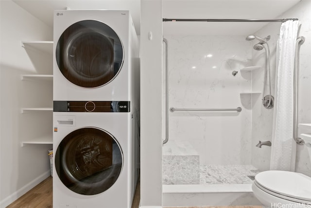 interior space with hardwood / wood-style flooring, stacked washer and dryer, toilet, and a shower with shower curtain