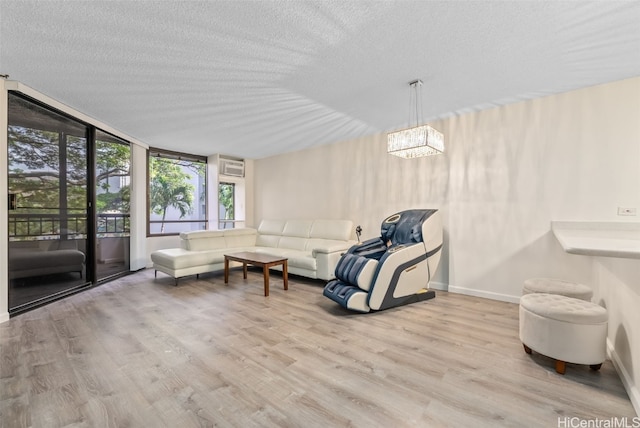 living room with a notable chandelier, a wall of windows, a textured ceiling, and light wood-type flooring