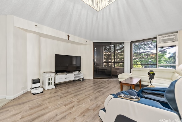 living room featuring a textured ceiling, a wall unit AC, and light wood-type flooring