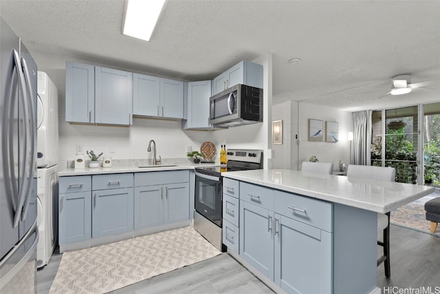 kitchen featuring sink, stainless steel appliances, a breakfast bar, and a textured ceiling