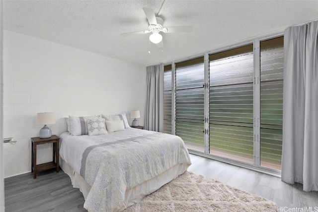 bedroom with ceiling fan, hardwood / wood-style floors, floor to ceiling windows, a textured ceiling, and access to outside