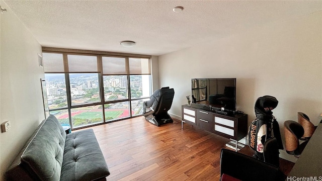 living room with hardwood / wood-style floors, a wall of windows, and a textured ceiling