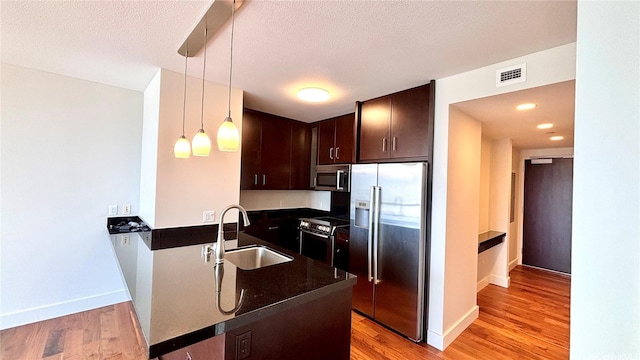 1189 Waimanu St Unit 3107, Honolulu, HI 96814 - kitchen with appliances with stainless steel finishes, a sink, dark brown cabinets, a peninsula, and light wood-style flooring