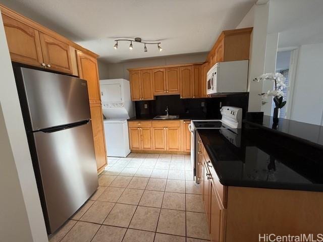 kitchen featuring backsplash, sink, white appliances, stacked washer and dryer, and light tile patterned floors