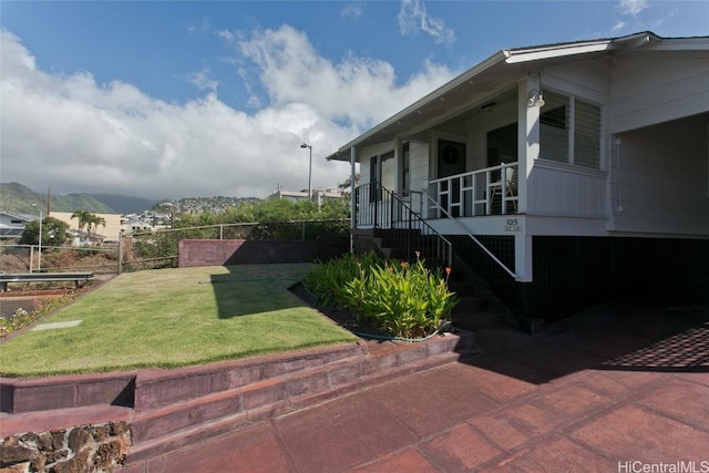 view of side of home featuring a mountain view, a porch, and a lawn