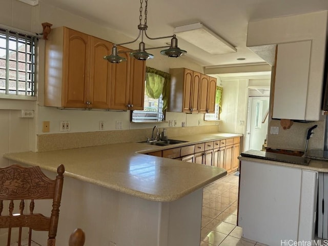 kitchen with kitchen peninsula, sink, light tile patterned flooring, and decorative light fixtures