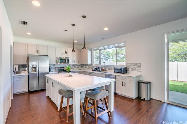 kitchen featuring appliances with stainless steel finishes, a breakfast bar, sink, pendant lighting, and a center island