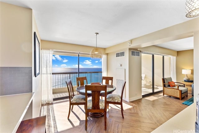 dining area featuring light parquet flooring and a water view