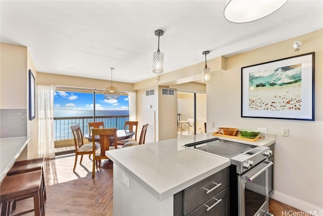 kitchen with decorative light fixtures, a water view, stainless steel range with electric cooktop, and dark parquet flooring