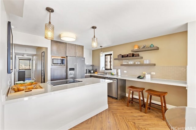 kitchen featuring sink, pendant lighting, light parquet floors, and stainless steel appliances