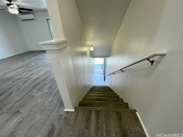 staircase featuring a wall unit AC, ceiling fan, and hardwood / wood-style floors