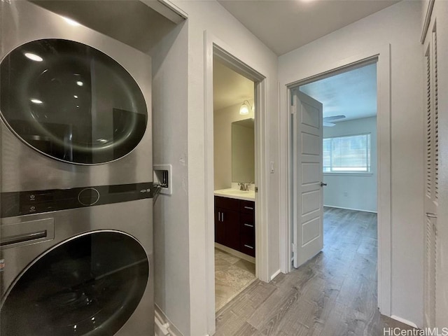 laundry room with sink, stacked washer and dryer, and light hardwood / wood-style flooring