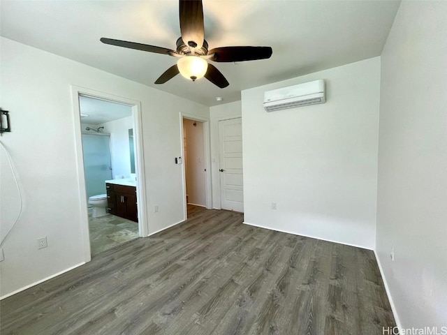 unfurnished bedroom featuring a wall mounted air conditioner, ceiling fan, hardwood / wood-style floors, and connected bathroom