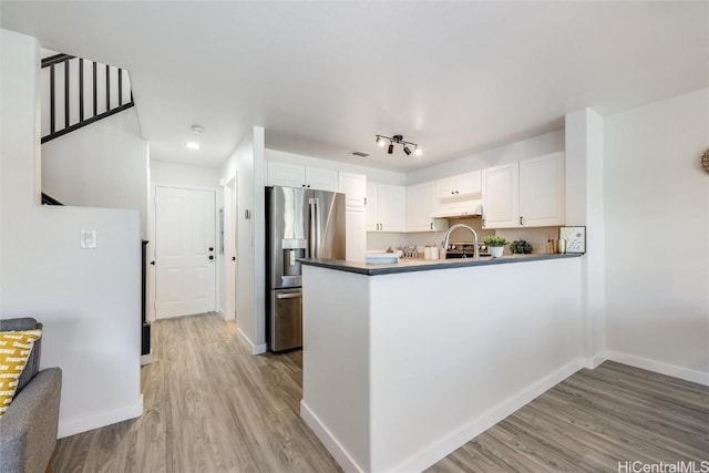 kitchen with light wood-type flooring, kitchen peninsula, white cabinets, and stainless steel refrigerator with ice dispenser