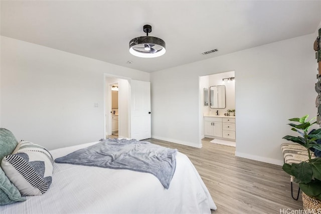 bedroom with connected bathroom and light hardwood / wood-style floors