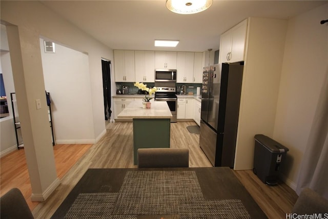 kitchen with stainless steel appliances, a center island, light wood-type flooring, and white cabinets