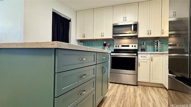 kitchen featuring tasteful backsplash, light wood-type flooring, white cabinets, and appliances with stainless steel finishes