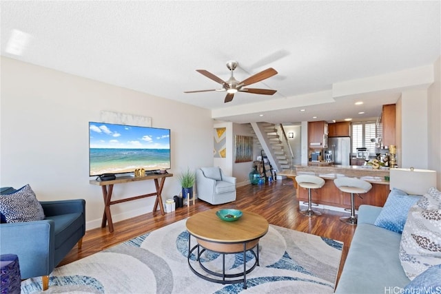 living room featuring dark wood-type flooring, ceiling fan, and a textured ceiling