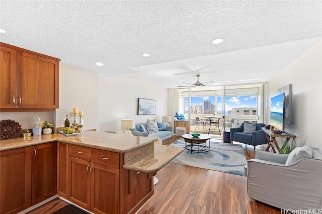 kitchen featuring a wall of windows, ceiling fan, kitchen peninsula, dark wood-type flooring, and a textured ceiling