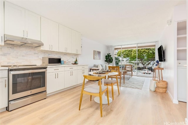 kitchen featuring backsplash, white cabinets, expansive windows, appliances with stainless steel finishes, and light hardwood / wood-style floors