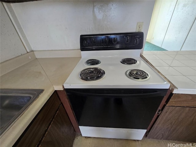 kitchen featuring tile countertops, sink, dark brown cabinets, and electric range oven