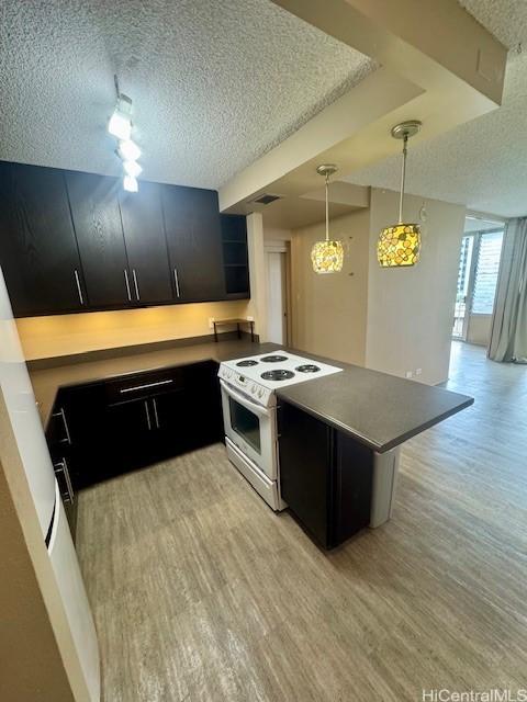 kitchen featuring pendant lighting, electric range, light hardwood / wood-style floors, a textured ceiling, and kitchen peninsula