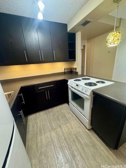 kitchen featuring built in desk, decorative light fixtures, white electric stove, a textured ceiling, and light hardwood / wood-style flooring