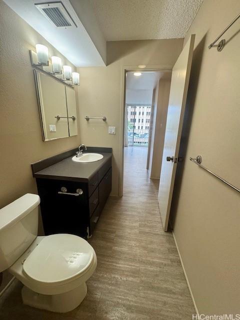 bathroom featuring hardwood / wood-style flooring, vanity, a textured ceiling, and toilet