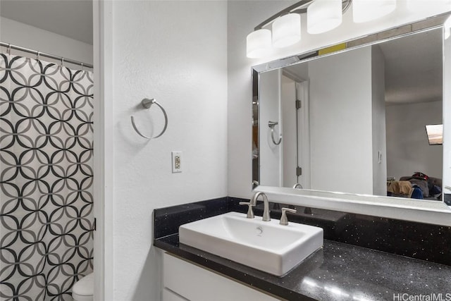 bathroom with toilet, curtained shower, and vanity