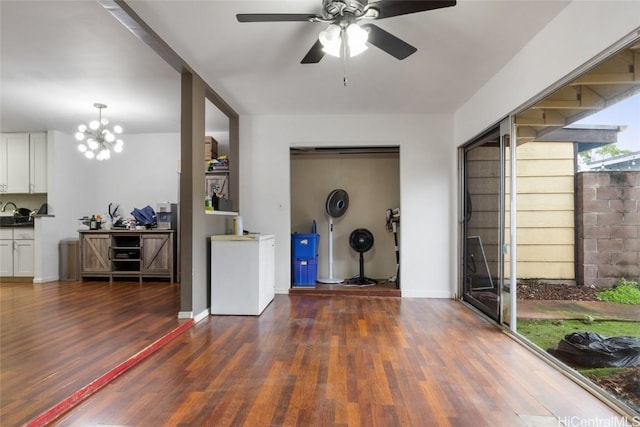 interior space with ceiling fan with notable chandelier and dark wood-type flooring