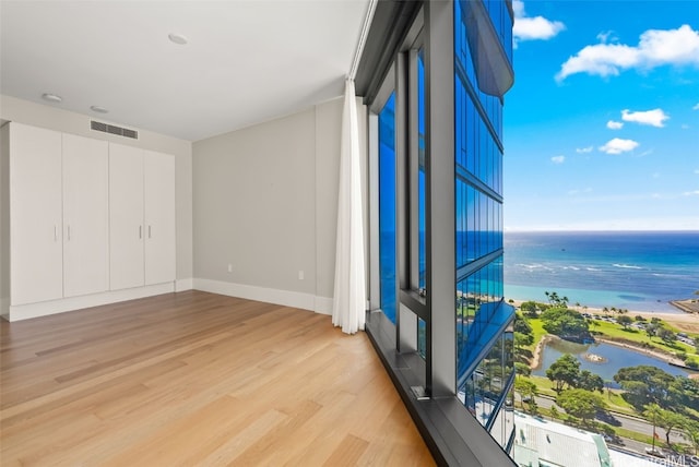 unfurnished bedroom featuring light hardwood / wood-style flooring and a water view