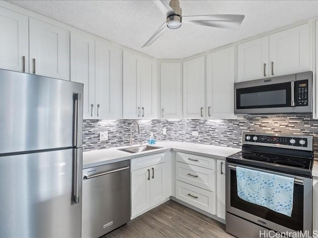 kitchen with ceiling fan, stainless steel appliances, tasteful backsplash, white cabinets, and sink