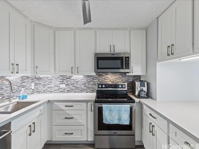 kitchen with appliances with stainless steel finishes, decorative backsplash, white cabinetry, and sink