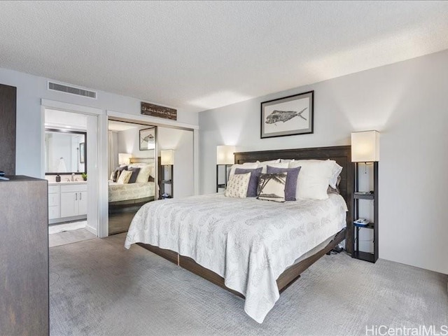 bedroom featuring a textured ceiling, light carpet, and ensuite bath