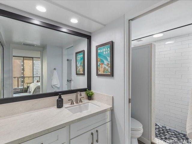 bathroom featuring toilet, vanity, and tiled shower