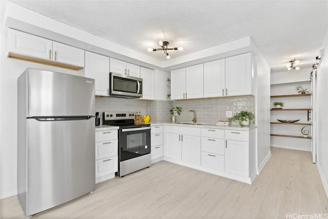 kitchen featuring white cabinets, appliances with stainless steel finishes, backsplash, and sink