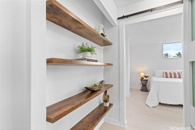 corridor with a barn door and light hardwood / wood-style flooring