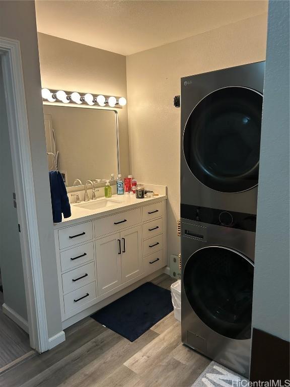 bathroom with vanity, stacked washer / drying machine, and hardwood / wood-style floors