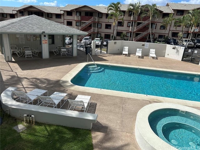 community pool with a patio area, fence, and a community hot tub