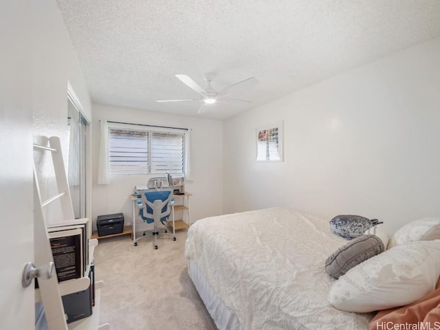 carpeted bedroom featuring ceiling fan and a textured ceiling