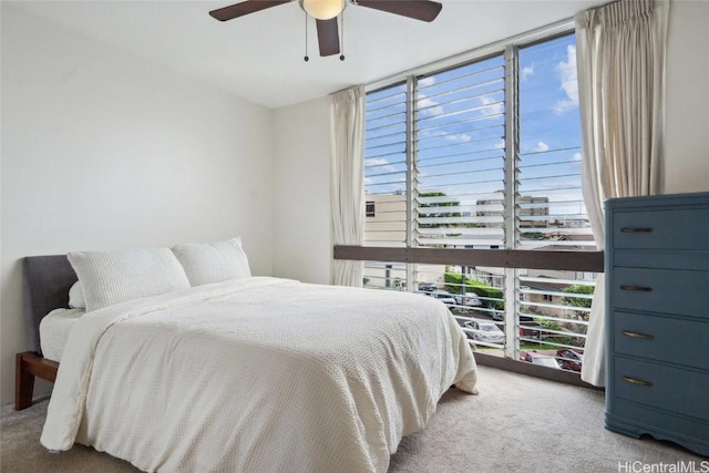 bedroom with multiple windows, ceiling fan, light colored carpet, and floor to ceiling windows